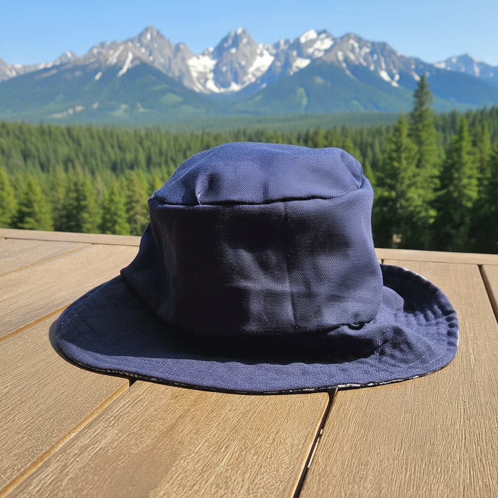 A navy blue wide-brimmed bucket hat resting on a light brown wooden deck with green trees in the background.