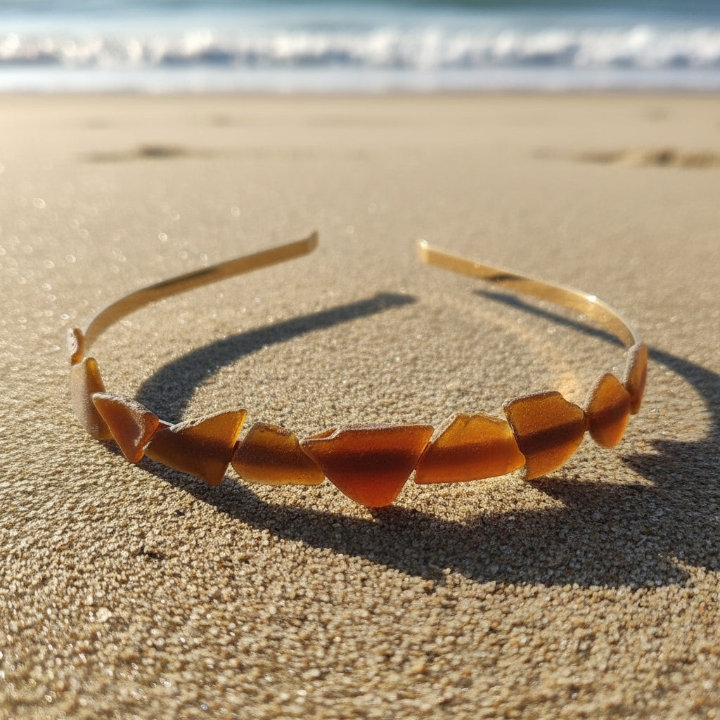 A thin headband made of multiple small curved amber-brown pieces, photographed outdoors on a wooden table with blurred greenery in the background.