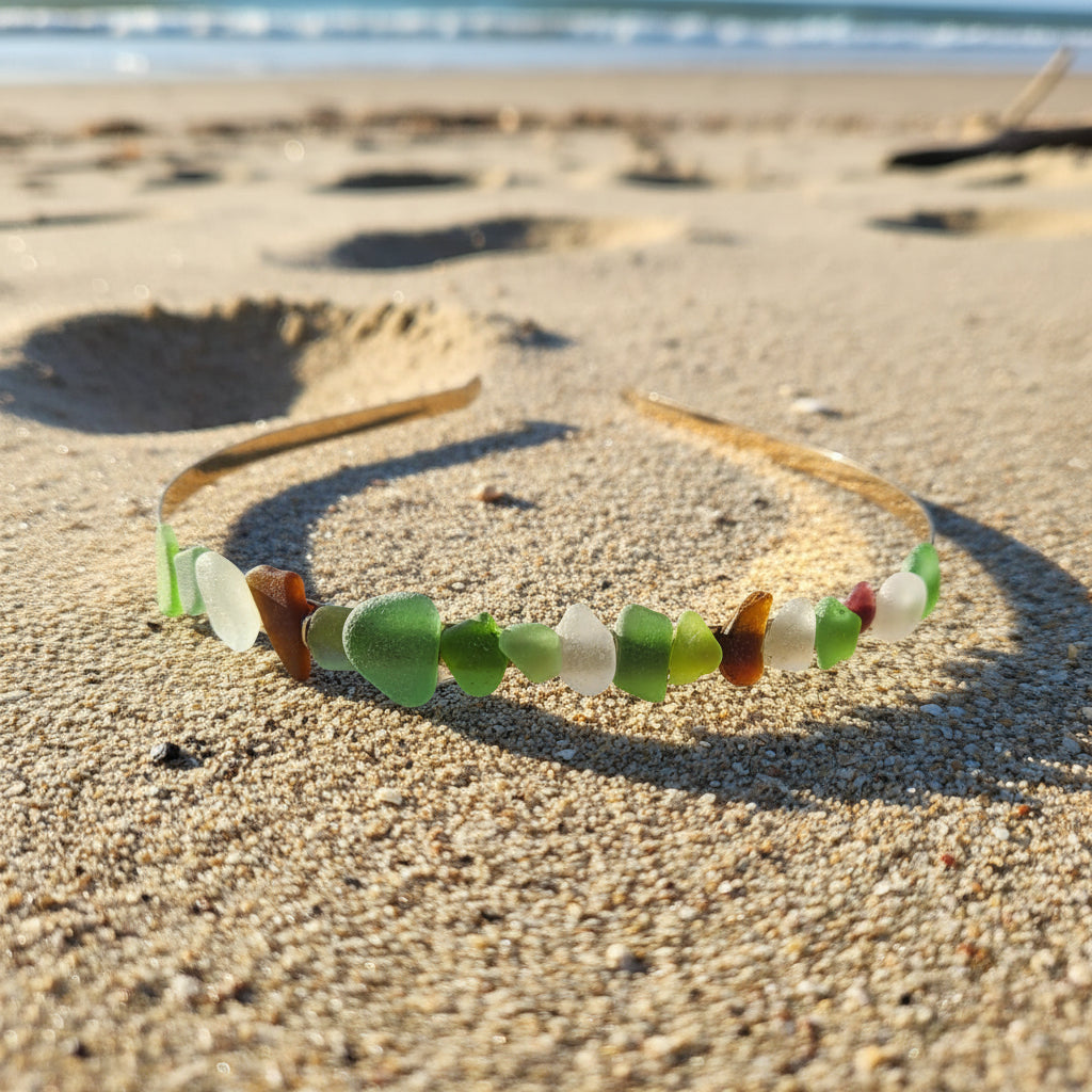 A headband decorated with small natural leaf pieces in shades of green, brown, and beige, resting on a wooden table outdoors.