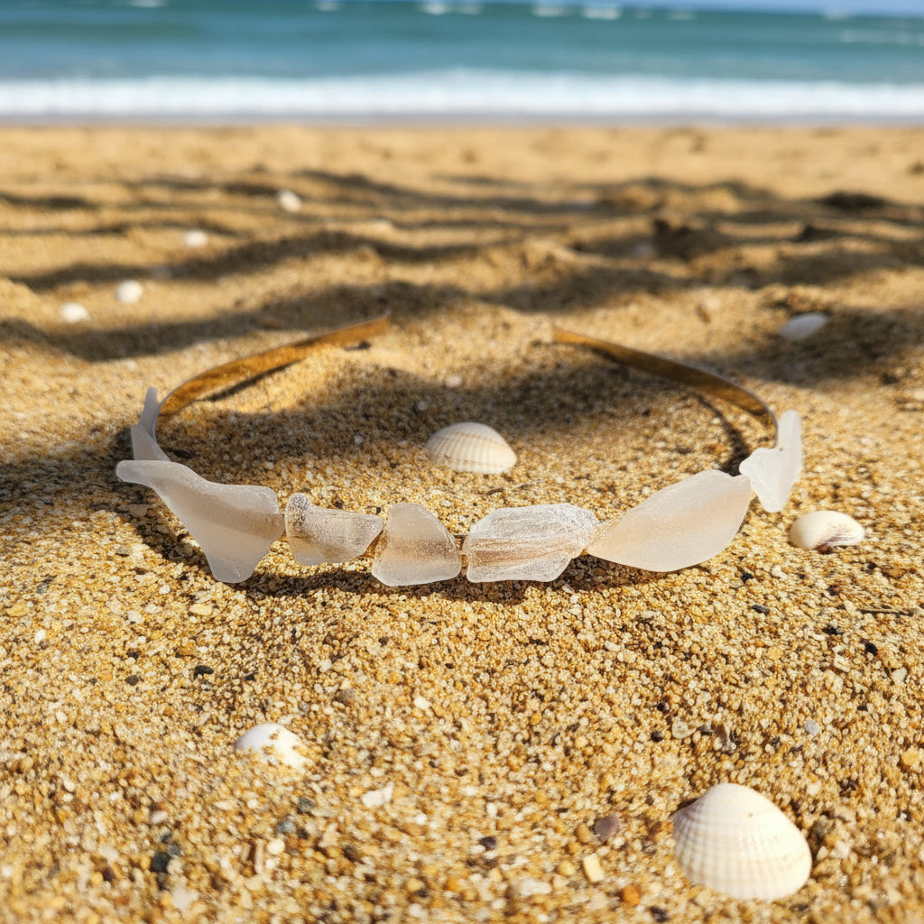 A natural white seashell headband resting on a brown wooden deck table outdoors.