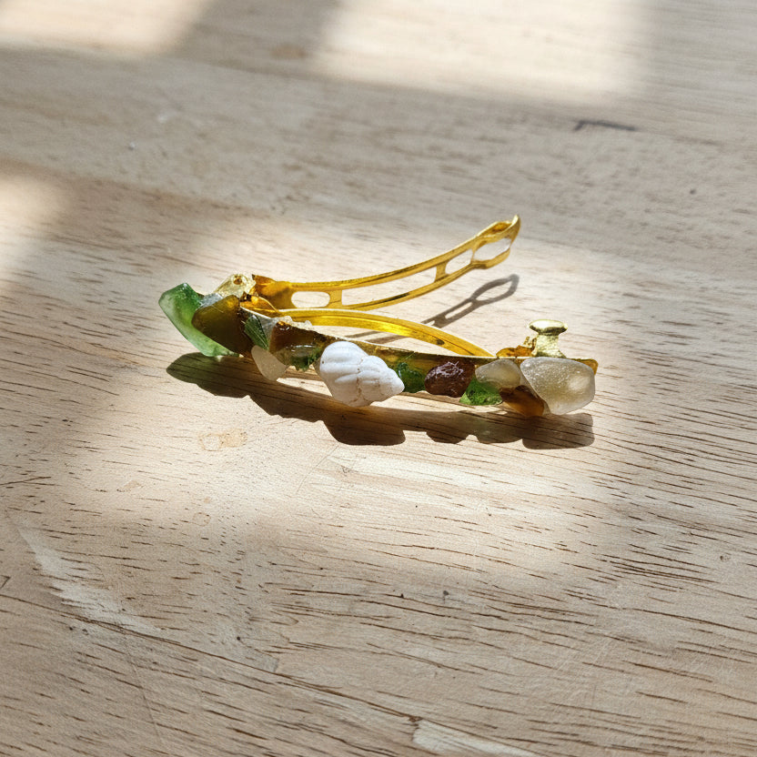 Gold hair clip with green stones on a wooden surface