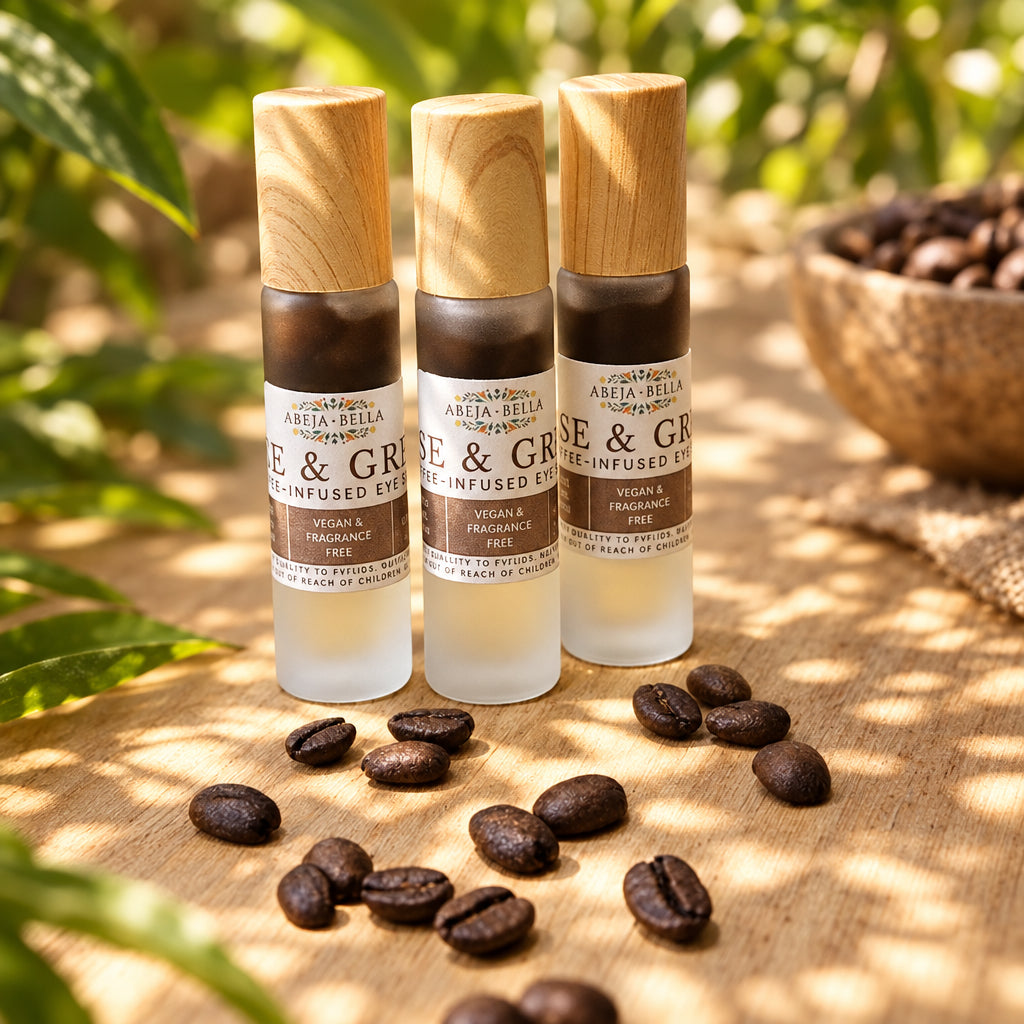 Three small glass roller bottles with light wood caps stand on a wooden surface, with scattered coffee beans in front and a light wood paneled background behind them.