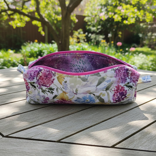 Pink fabric pouch with floral pattern on a wooden surface