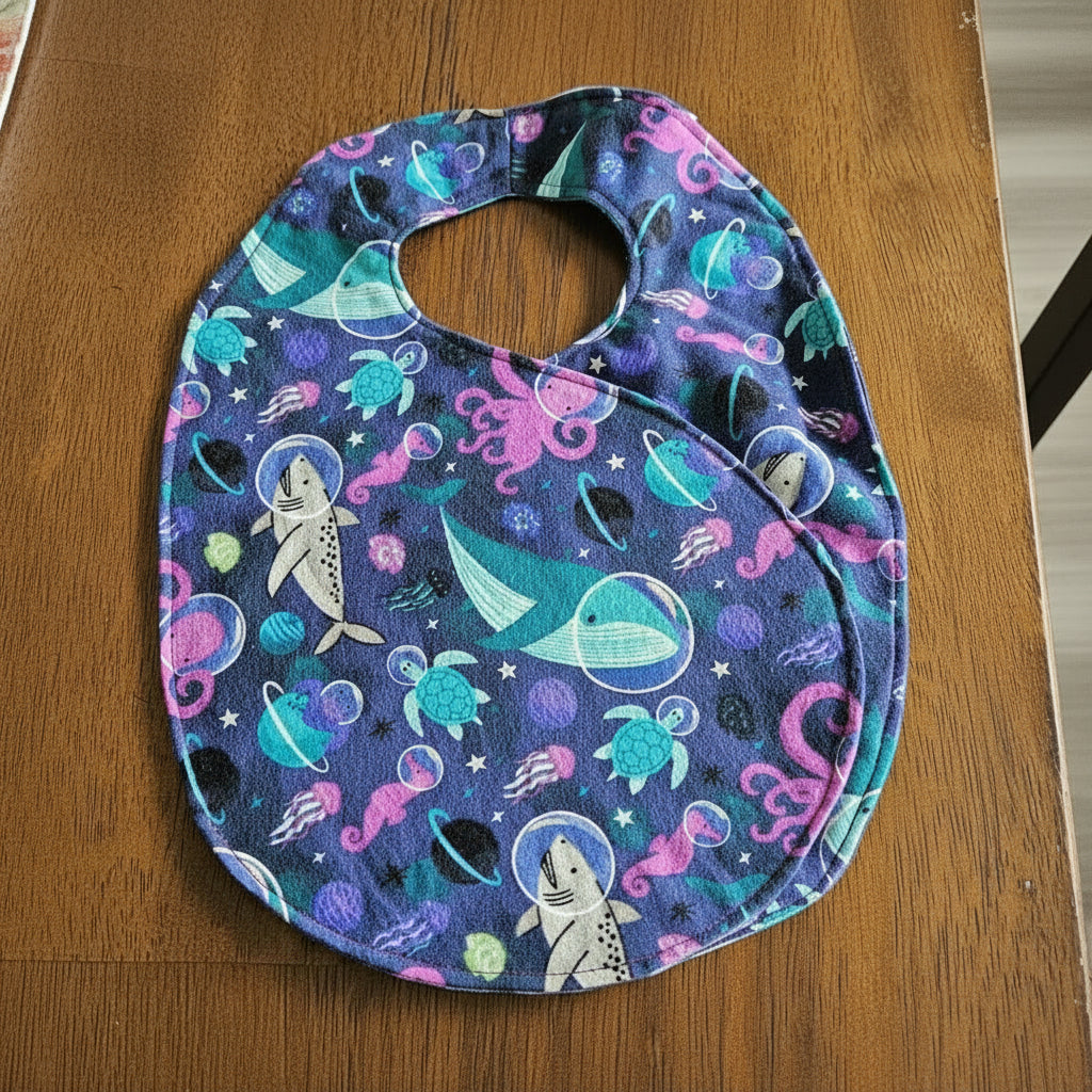 Baby bib with ocean-themed print on a wooden surface