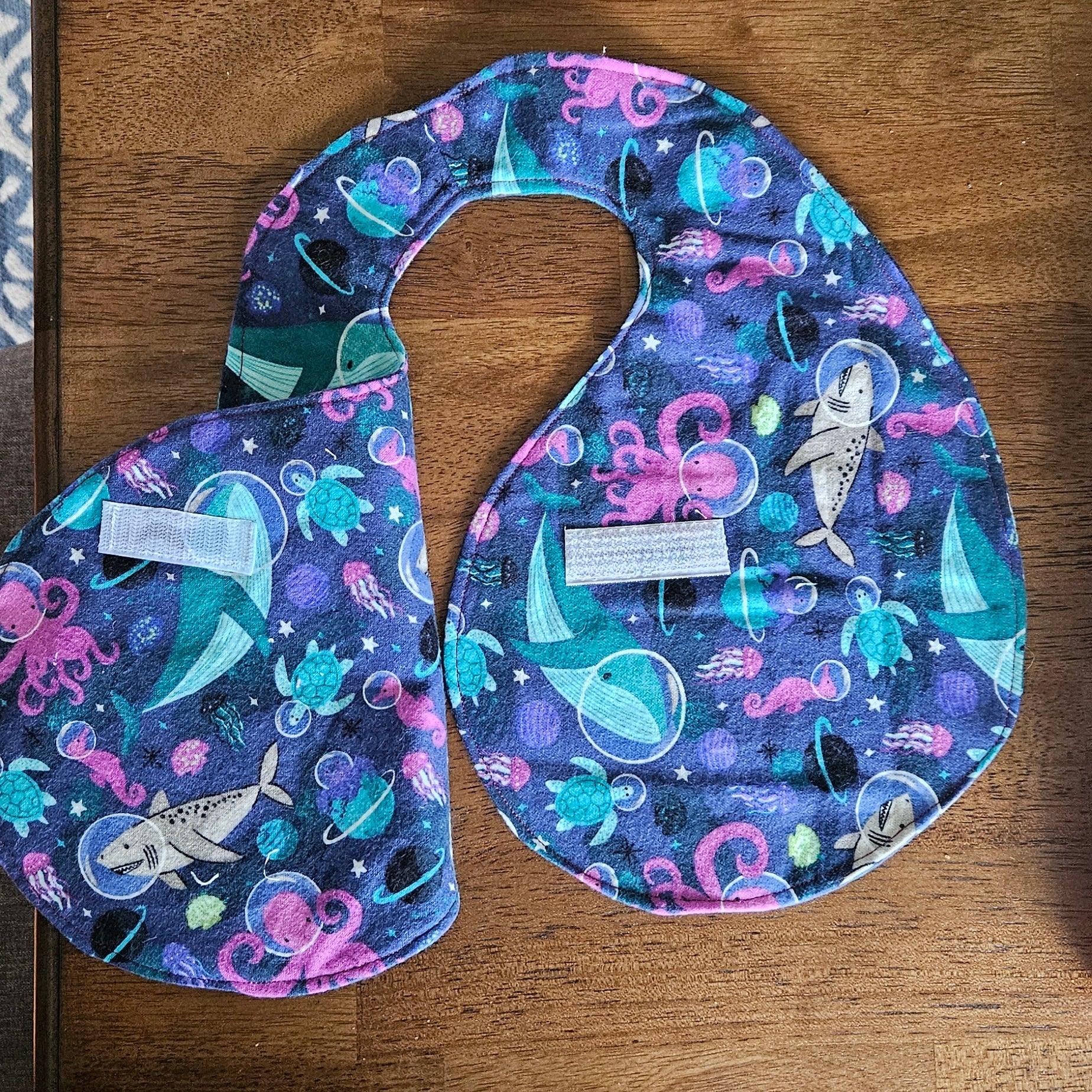 Colorful baby bib and burp cloth set on a wooden surface