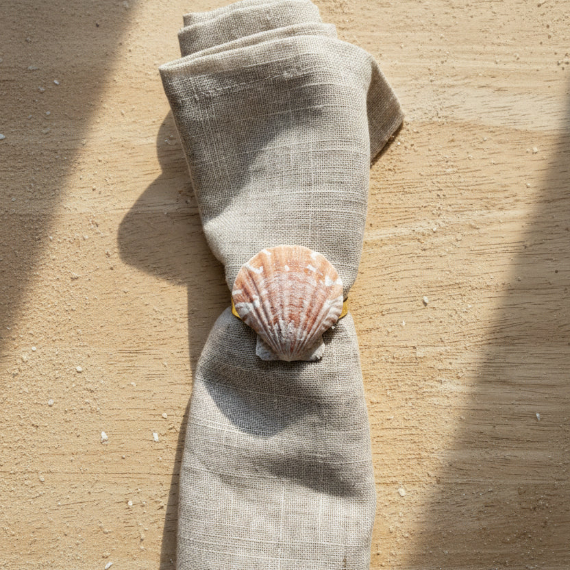 Folded beige fabric with a shell on a wooden surface