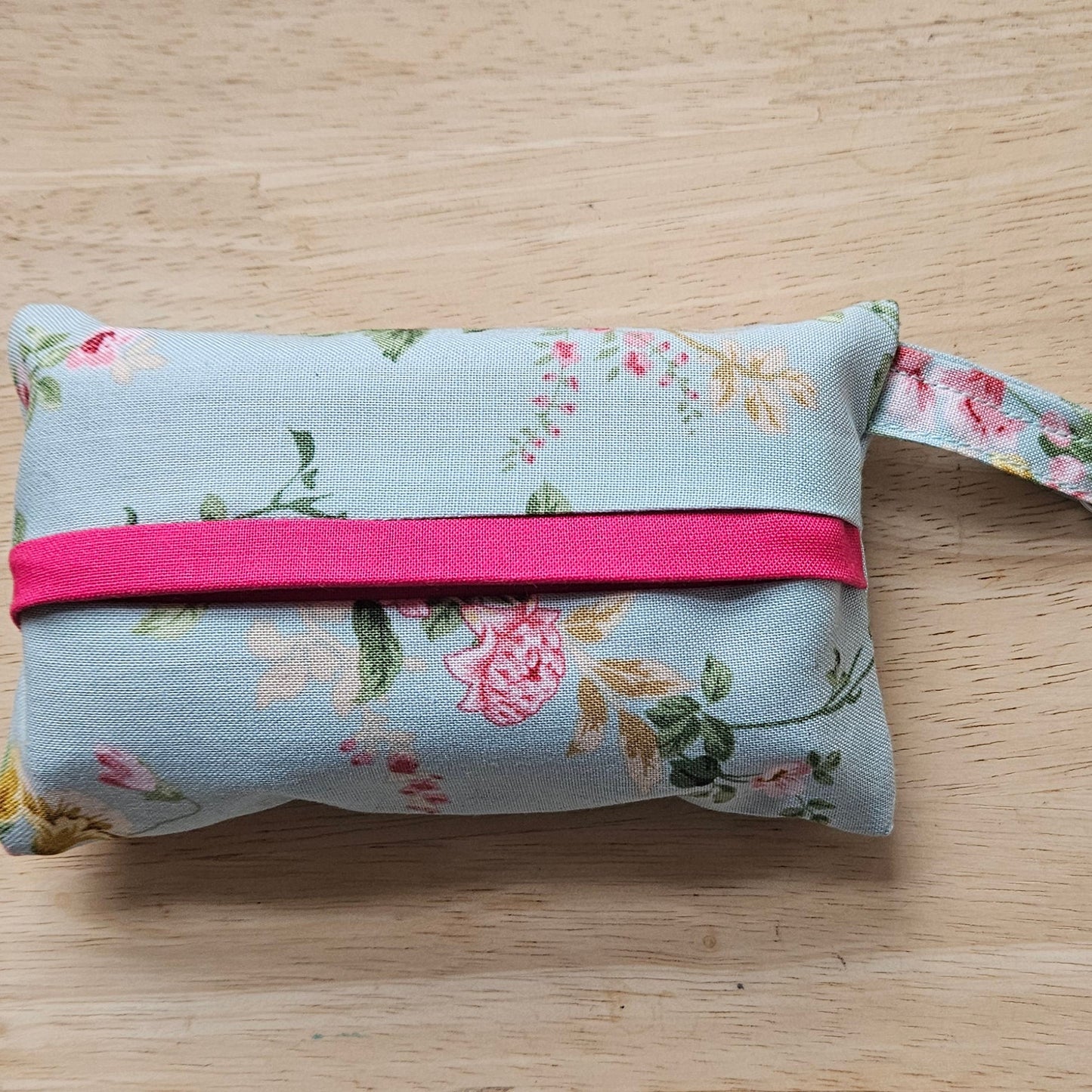 Floral fabric pouch with a pink strap on a wooden surface