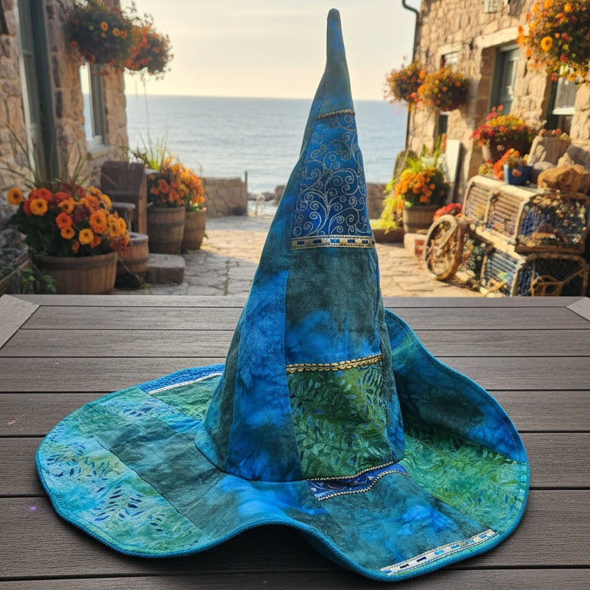 A handmade wizard hat made from blue and green marbled fabric, resting on a wooden deck with a backyard garden in the background.
